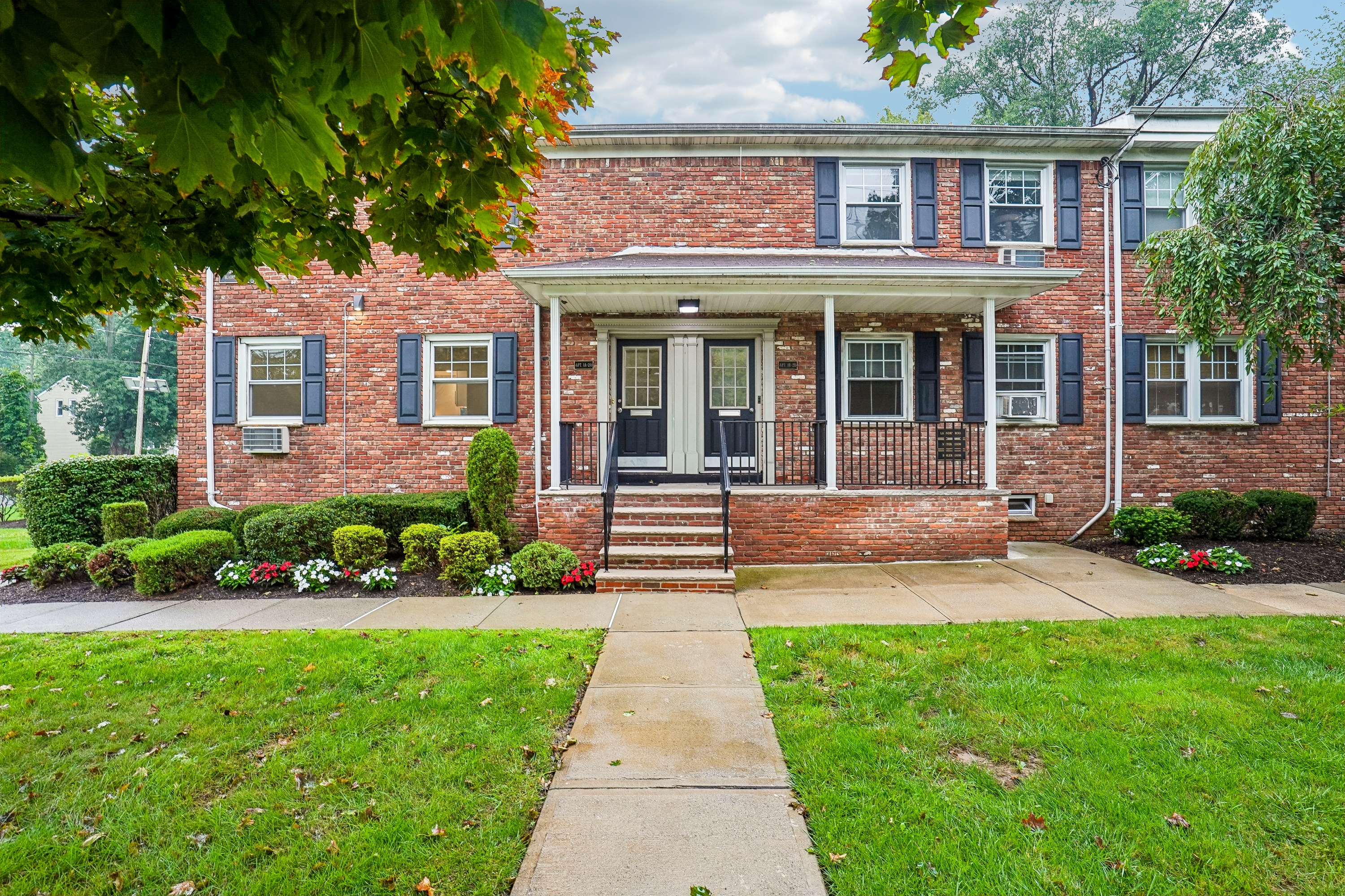 A red brick house with a white door and black shutters.
